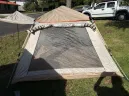 4 person camping tent side view with extended awning and mesh windows set up on grass