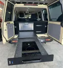 Evakool 40L Platinum Drawer10 > 4wd Lights and Camping Online Store Campervan rear with a pull-out kitchen: black countertop, two-burner induction stove, and fridge drawer inside open doors