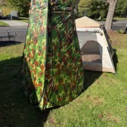 Portable shower tent set up beside camping tent for a complete campsite setup